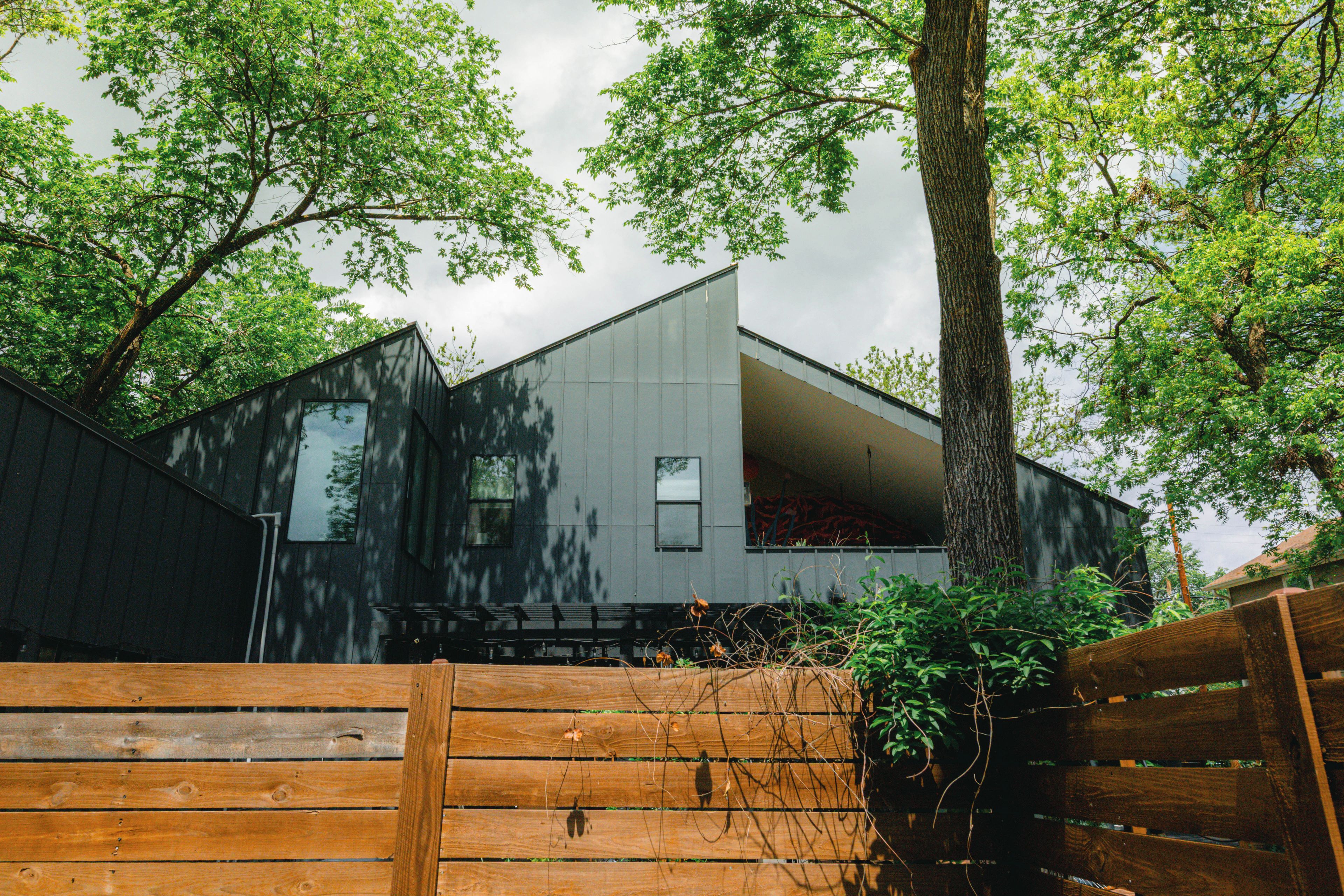 A modern building with a sloped roof, surrounded by trees.