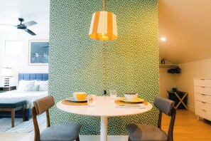 A dining area with a round table, chairs, and a hanging lamp.