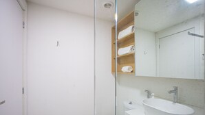 A bathroom with a white sink, a mirror, and a wooden shelf with towels. - Nex One Paraiso (São Paulo)