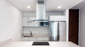 A modern kitchen with a central island, stainless steel appliances, and white cabinetry. - Beautiful One-Bedroom, Two-Full-Bathroom Condo Just Steps from the Beach! (Playa del Carmen)