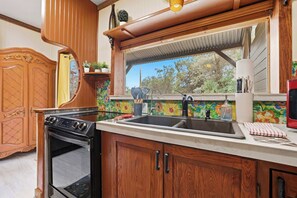 A kitchen with a double sink, stove, and wooden cabinets. - Private Prescott Studio | Full Kitchen (Prescott)