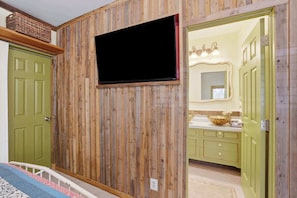 Ein Zimmer mit einer Wandpaneele aus Holz, einem Fernseher über einer Tür und einer grünen Tür.