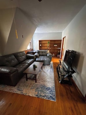A living room with a sofa set, a coffee table, a TV, and a bookshelf.