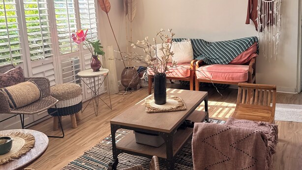 Ein Wohnzimmer mit Deckenventilator, einer Couch, einem Couchtisch und einem Essbereich.