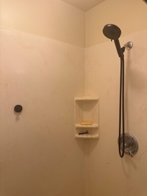 Eine Dusche mit Duschbrause, Seifenschale und Handtuchhalter.