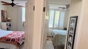 Ein Schlafzimmer mit Bett, Kleiderschrank, Deckenventilator und einer Tür zu einem anderen Raum.