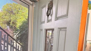Eine Tür mit Insektenschutzgitter, ein Fenster mit dekorativem Glas und ein Klingel.