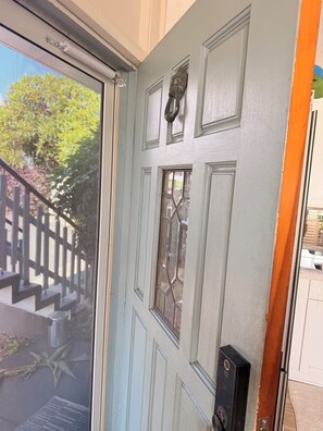 Eine Tür mit Insektenschutzgitter, ein Fenster mit dekorativem Glas und ein Klingel.