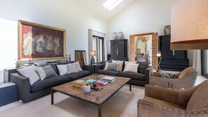 Ein Wohnzimmer mit einer Couch, Sesseln, einem Couchtisch und einem Gemälde.