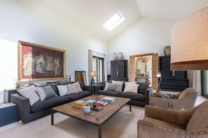 Ein Wohnzimmer mit einer Couch, Sesseln, einem Couchtisch und einem Gemälde.