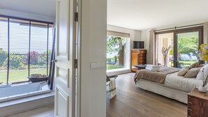 Ein Schlafzimmer mit großem Fenster, einem Bett, einem Fernseher und Blick ins Freie.