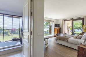 Ein Schlafzimmer mit großem Fenster, einem Bett, einem Fernseher und Blick ins Freie.