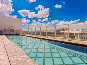 A rooftop pool with a cityscape view, surrounded by glass railings. - Villa Versace (São Paulo)