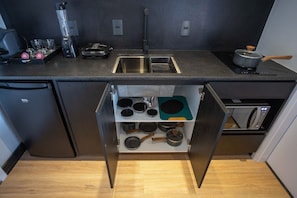 A kitchen with a built-in sink, a blender, a microwave, and a drawer with pots and pans. - Villa Versace (São Paulo)