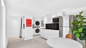 A modern kitchen with white cabinets, a stainless steel refrigerator, and a black oven.