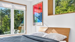 A bedroom with a bed, a window with a view of trees, and a poster on the wall.