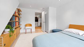 Une chambre avec un lit, une bibliothèque, une chaise et une vue sur la cuisine.