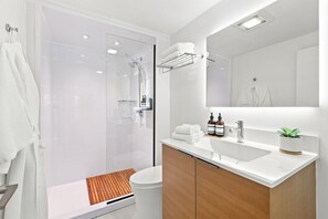 A modern bathroom with a glass-enclosed shower, a white sink, and a mirror above it.