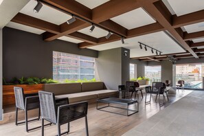 A modern lounge area with seating, a coffee table, and a view of the cityscape. - VN Capote Valente (São Paulo)
