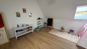 Un cuarto infantil con un estante blanco, una pizarra y una ventana con vistas.