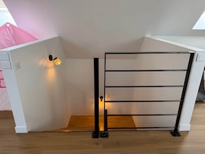 Ett vitt rum med ett svart metallställ, ett trägolv och en väggmonterad lampa.