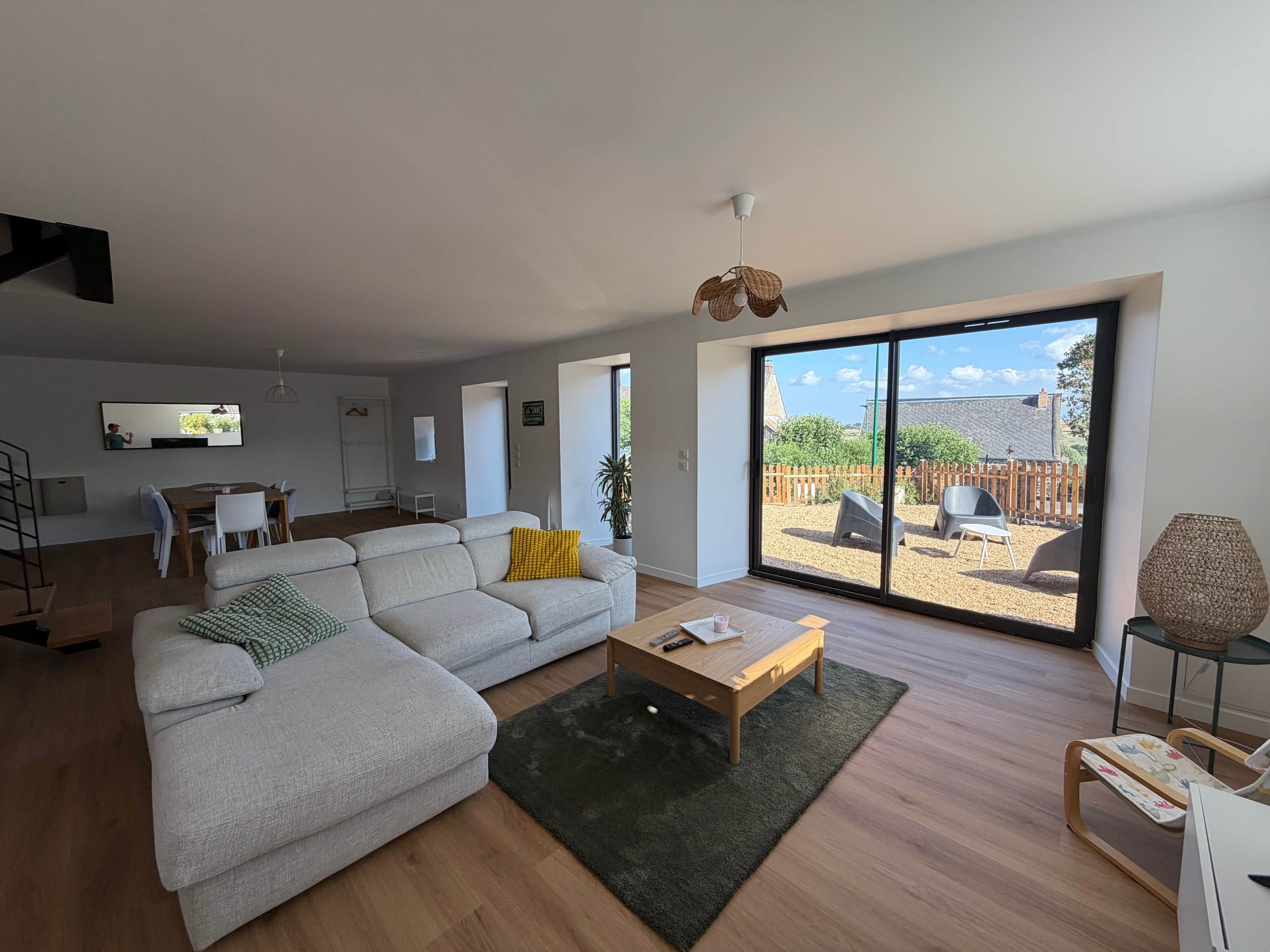 A modern living room with a sofa, coffee table, and a view of the backyard through large sliding doors.