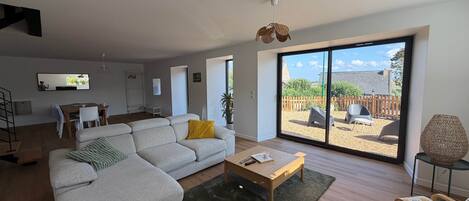 A modern living room with a sofa, coffee table, and a view of the backyard through large sliding doors.