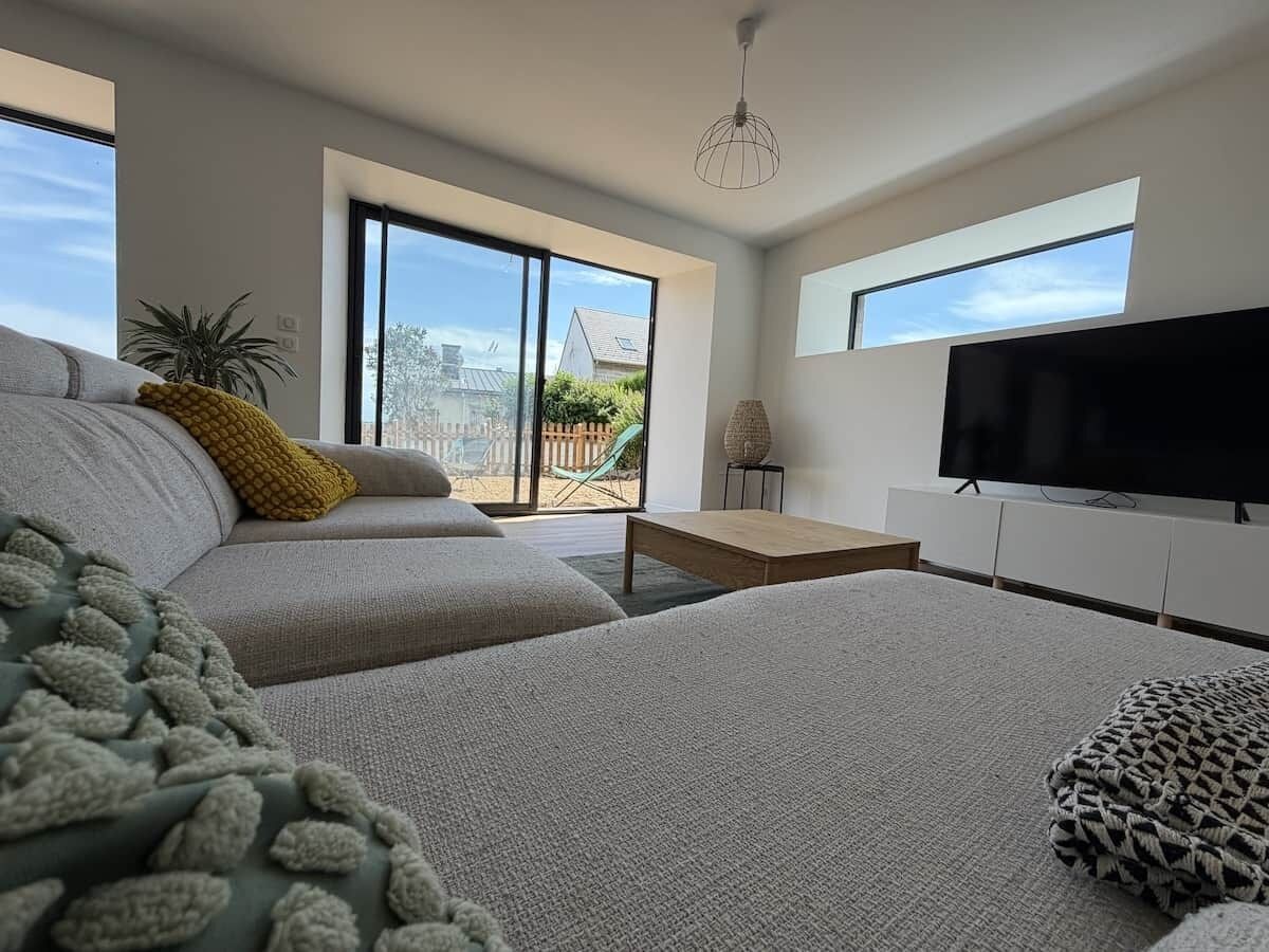 Una sala de estar moderna con un sofá, una mesa de centro, un televisor de pantalla plana y vistas al exterior.