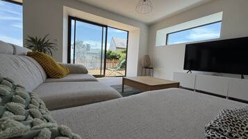 Una sala de estar moderna con un sofá, una mesa de centro, un televisor de pantalla plana y vistas al exterior.