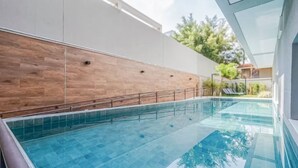 A swimming pool with clear water, surrounded by a wooden wall and a white building. - Welconx Vila Olimpia (São Paulo)
