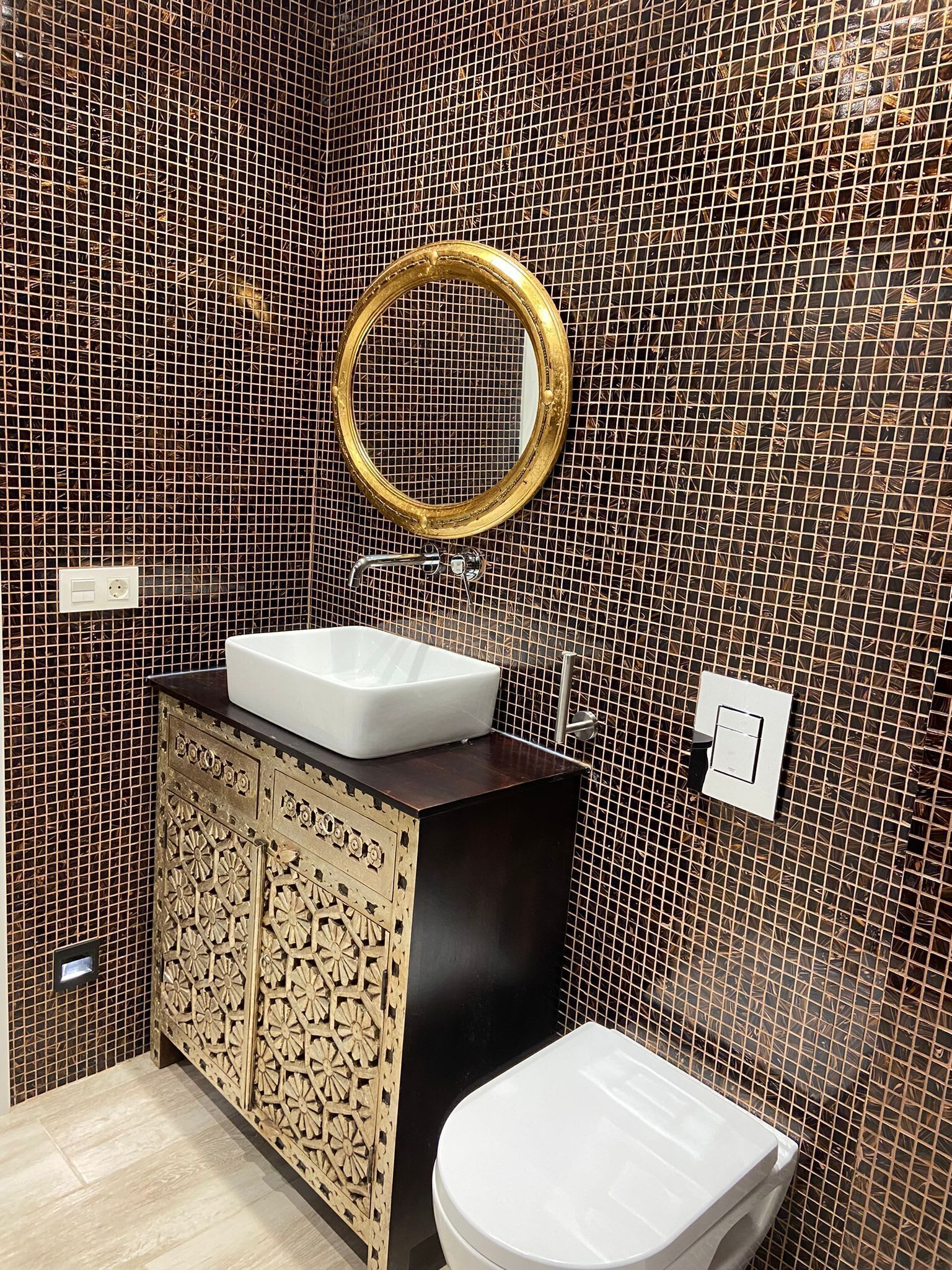 Ein Badezimmer mit Waschbecken, Toilette und einem dekorativen Spiegel.