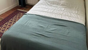A bedroom with a bed, a radiator, a window with curtains, and a patterned rug. - Cozy house in Bordeaux in beautiful central neighborhood - near sights and tram (Bordeaux)