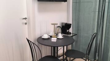 Un'area ristoro con un tavolo rotondo, quattro sedie, una macchina da caffè, un bollitore e un televisore a schermo piatto montato a parete.
