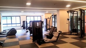 A gym with exercise equipment, large windows, and a checkered floor. - Zip Brooklin (São Paulo)