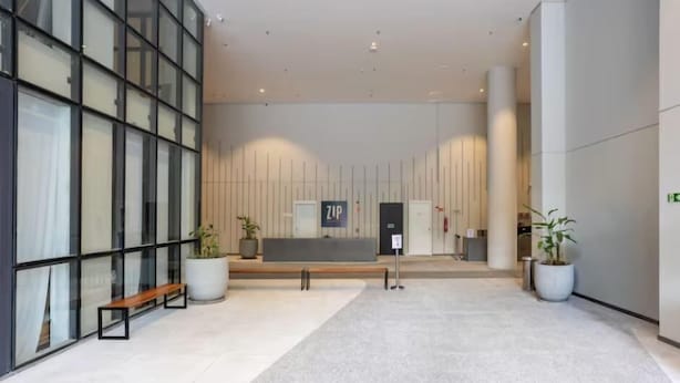 A modern lobby with a reception desk, seating area, and potted plants. - Zip Brooklin (São Paulo)