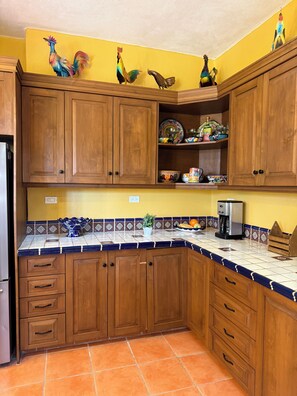 Eine Küche mit Holzausstattung, einer Kaffeemaschine und Wanddekorationen mit Hahn-Motiven.