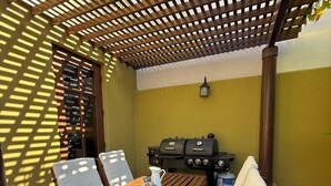 A patio with a wooden table and chairs, a grill, and a pergola structure. - Villa Amore (Nopolo)
