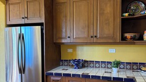 A kitchen with wooden cabinets, a stainless steel refrigerator, and decorative wall art. - Villa Amore (Nopolo)