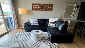 Een moderne woonkamer met een zwarte leren bank, een ronde salontafel en een kamerkleed met dessin.