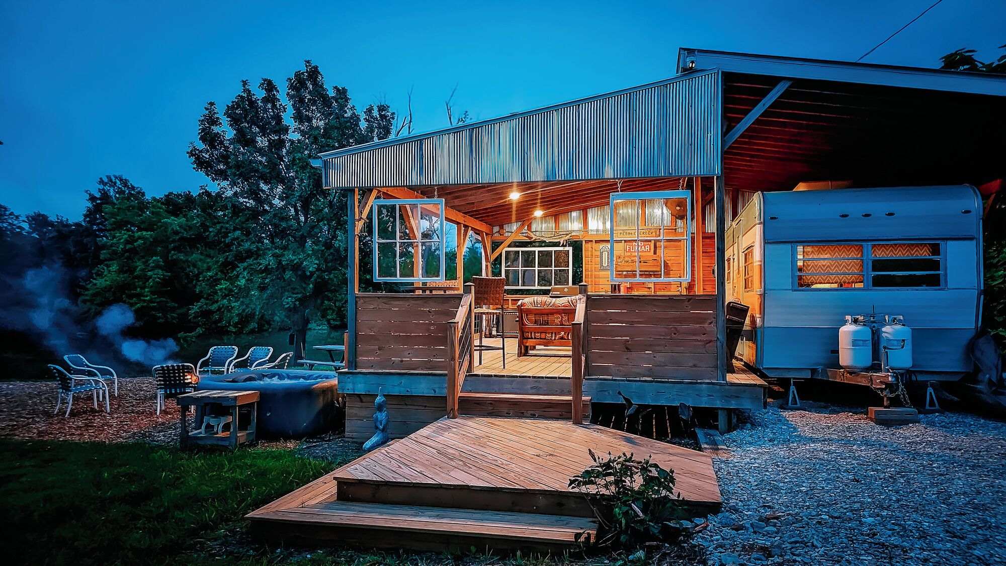 A wooden cabin with a covered porch, a dining area, and a small outdoor seating space.