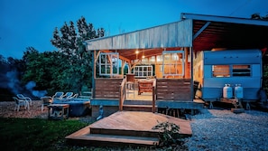 A wooden cabin with a covered porch, a dining area, and a small outdoor seating space.