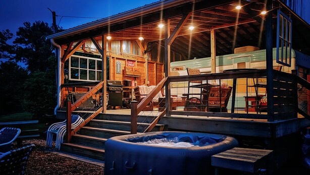 Un chalet rustique doté d’un porche couvert, d’un bain à remous et d’un espace repas avec des sièges extérieurs.