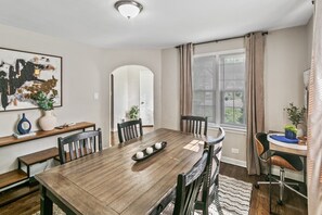 Ein Essbereich mit Holztisch, Stühlen, einer Vase und einem Bild an der Wand.