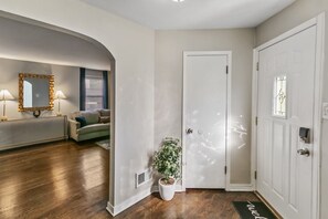 Ein Flur mit einer weißen Tür, einem Blumentopf, einem Heizkörper und einem Sofa.