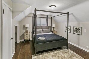 Ein Schlafzimmer mit Himmelbett, begehbarem Kleiderschrank und Kunstwerken an den Wänden.