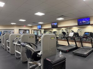 A gym with exercise equipment, treadmills, and a television screen. - Storybook Cabin-Hot Tub, Fire Pit & Tree Top Views (Ellijay)