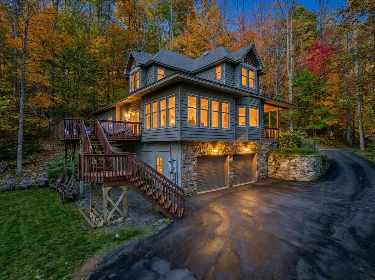A two-story house with a stone foundation, a wooden deck, and a garage.