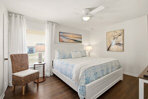 Ein Schlafzimmer mit einem Bett, einem Sessel, einem Deckenventilator und Bildern an den Wänden.
