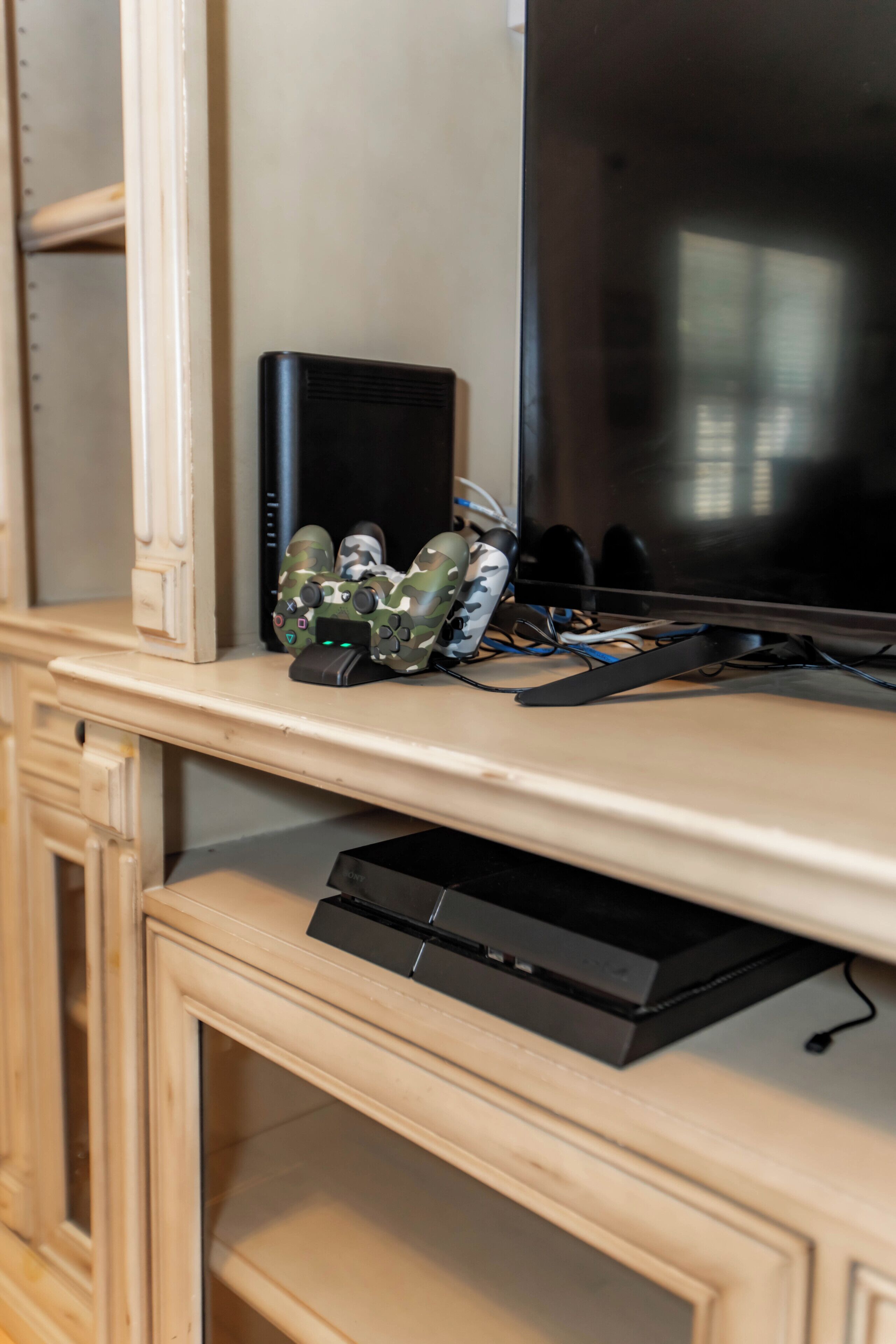 Una consola de videojuegos, un televisor y un aparador sobre una superficie de madera.