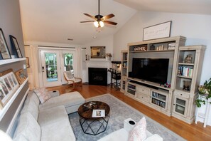 A living room with a sofa, coffee table, fireplace, TV, and bookshelves. - 4bdrm/Gym/Arcade/Theater/Jacuzzi (New Bern)